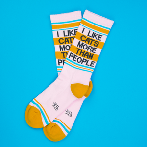 Lifestyle shot of two 'I Like Cats More Than People' socks on a blue background.