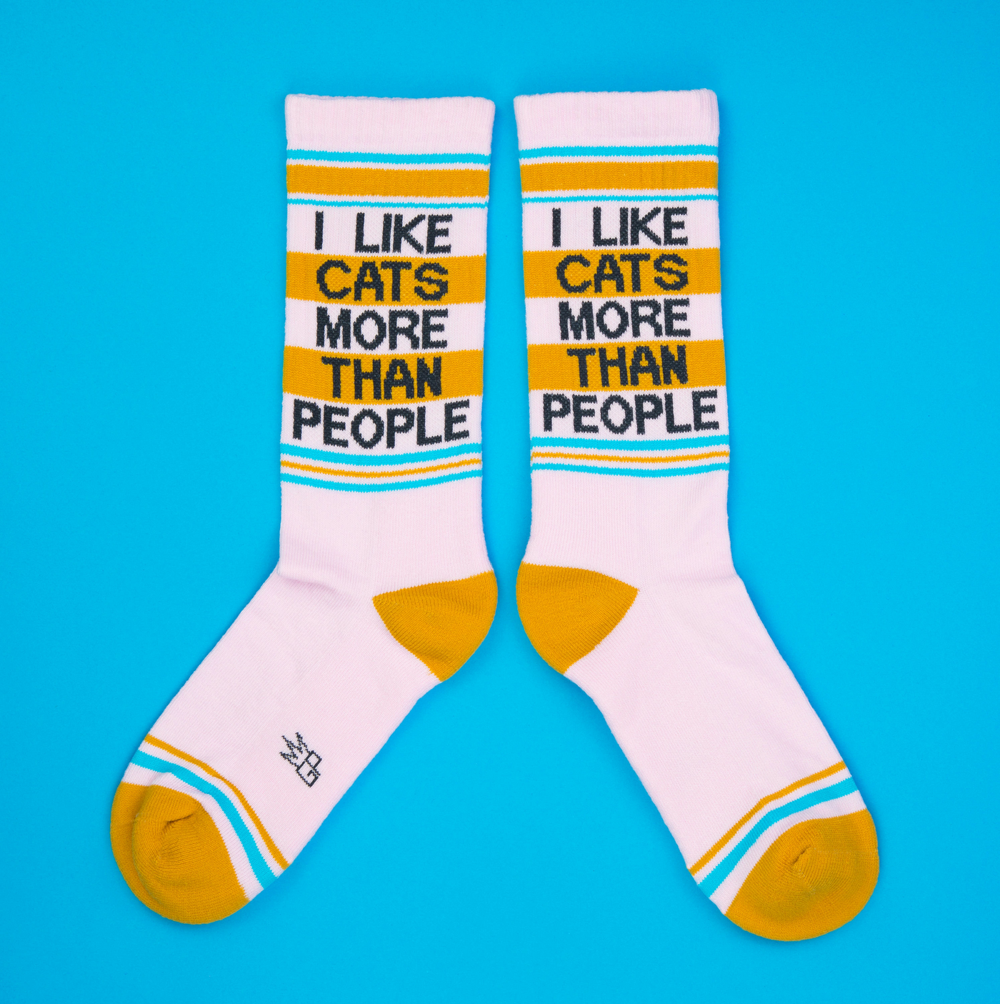 Flat lay of two 'I Like Cats More Than People' socks on a bright blue background.