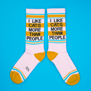 Flat lay of two 'I Like Cats More Than People' socks on a bright blue background.