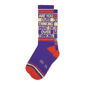 Pair of purple crew socks with orange and beige stripes and the text 'ARE YOU OVER THINKING WHAT I'M OVER THINKING' repeated.