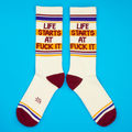 Flatlay product shot of a pair of 'Life Starts At Fuck It' socks on a bright blue background.