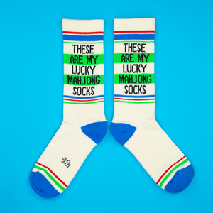 Flat lay product shot of a pair of 'These Are My Lucky Mahjong Socks' on a bright blue background.