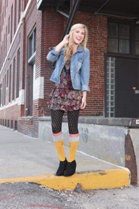 A young woman is wearing a floral dress, denim jacket, black boots, and yellow socks with polka dots.