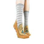 Lifestyle shot showing the moccasin slipper socks on a person's feet. Grey and tan colors are displayed.