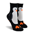 Pair of black crew socks with a white penguin design and orange heart-shaped feet. 