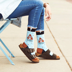 A person wearing blue jeans, brown leather sandals, and socks with a brown and blue poop emoji pattern and the text 