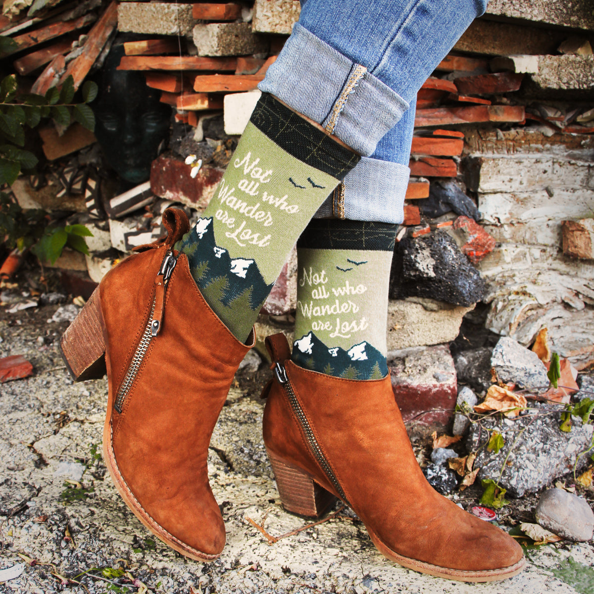 Lifestyle shot of Wanderer socks worn with brown ankle boots and jeans against a brick wall. [lf]