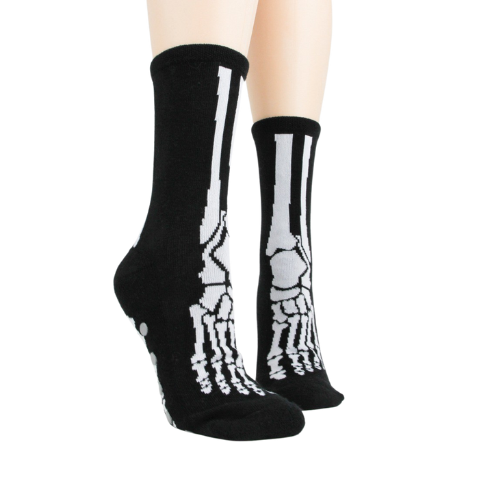 A pair of black socks with a white skeleton foot design on the bottom.