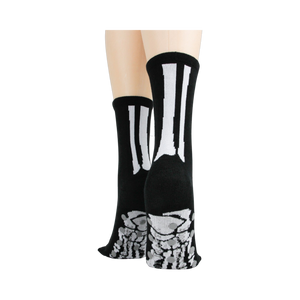 Rear view of model's legs wearing black skeleton socks with grey non-skid bottoms against a black background.