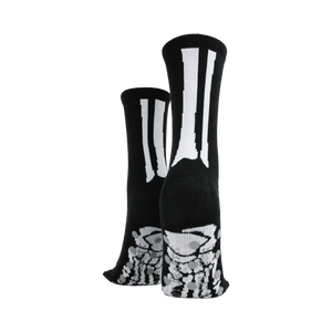 Rear view of model's legs wearing black skeleton socks with grey non-skid bottoms.