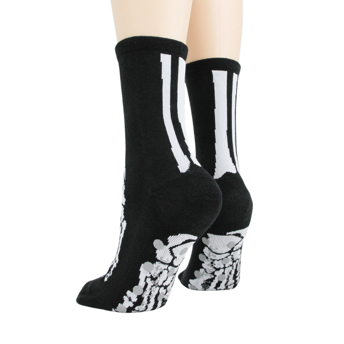 A pair of black socks with a white skeleton foot design on the bottom.