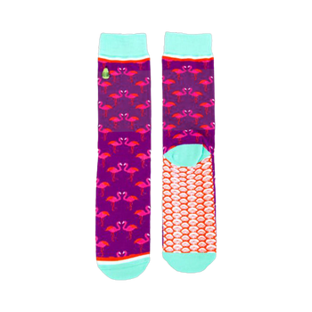 Pair of crew socks. Purple background with pink flamingo design. Teal cuffs and orange scale pattern on the soles.