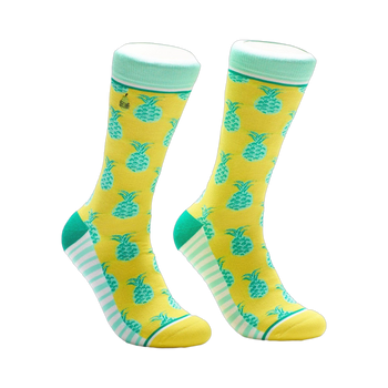A pair of crew socks in yellow with teal pineapples. The cuffs are mint green and white stripes accent the heel and toe.