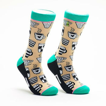 A pair of beige crew socks adorned with black and white illustrations of various coffee mugs and teacups. The socks have teal cuffs and black heels and toes.