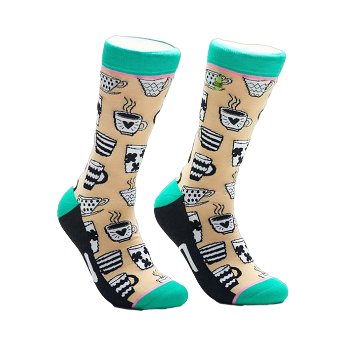 A pair of beige crew socks adorned with black and white illustrations of various coffee mugs and teacups. The socks have teal cuffs and black heels and toes. }}