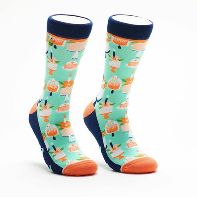mint green crew socks feature birthday cakes, candles, flowers, and "birthday girl" text. navy toe, heel, and upper band with white line. orange lining.   