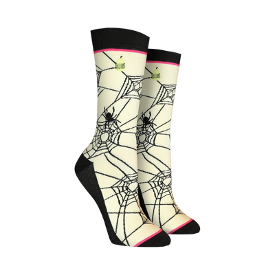 Pair of cream crew socks featuring a black spiderweb design, black spiders, and small lime green cupcake accents.