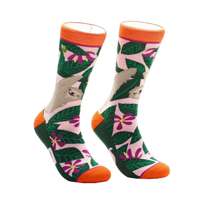 A pair of crew socks with a pink, green, and orange design.  The socks feature sloths hanging from tropical leaves and flowers. }}