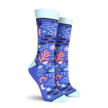 A pair of women's crew socks in blue, adorned with a whimsical undersea design featuring seahorses, coral, fish, and crabs.