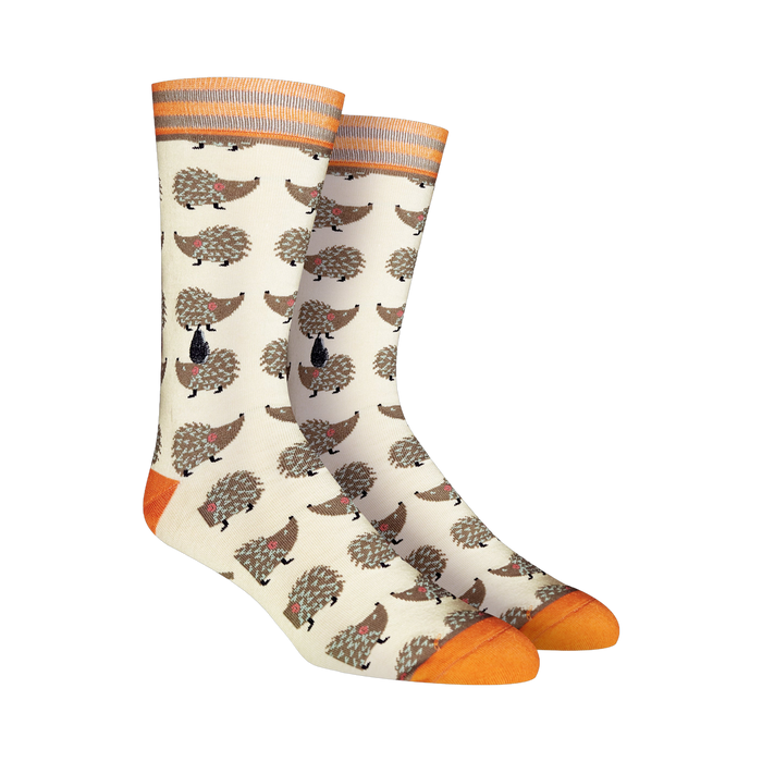 Cream crew socks featuring a repeating pattern of brown hedgehogs. Orange and gray stripes accent the cuffs and toes.