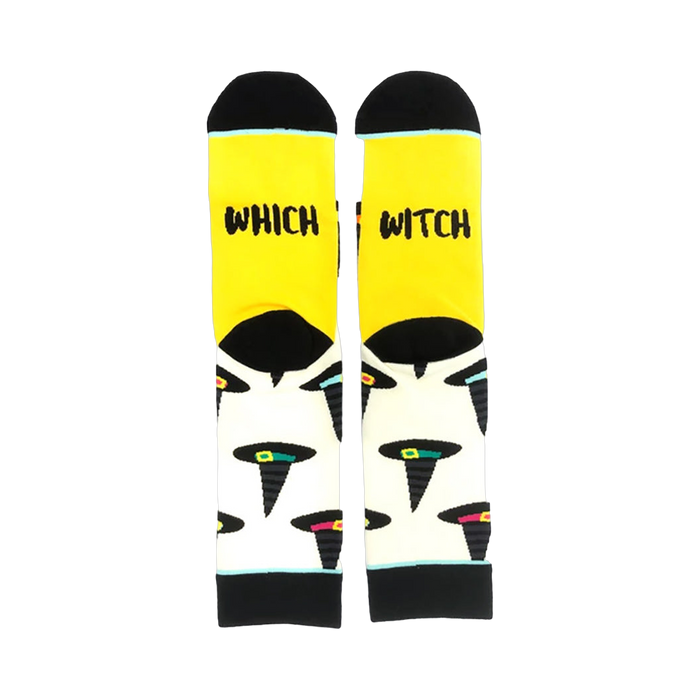 A pair of crew socks with a yellow cuff and cream body. The socks feature a pattern of black witch hats with colorful accents.  The cuff reads 'Which Witch'. }}