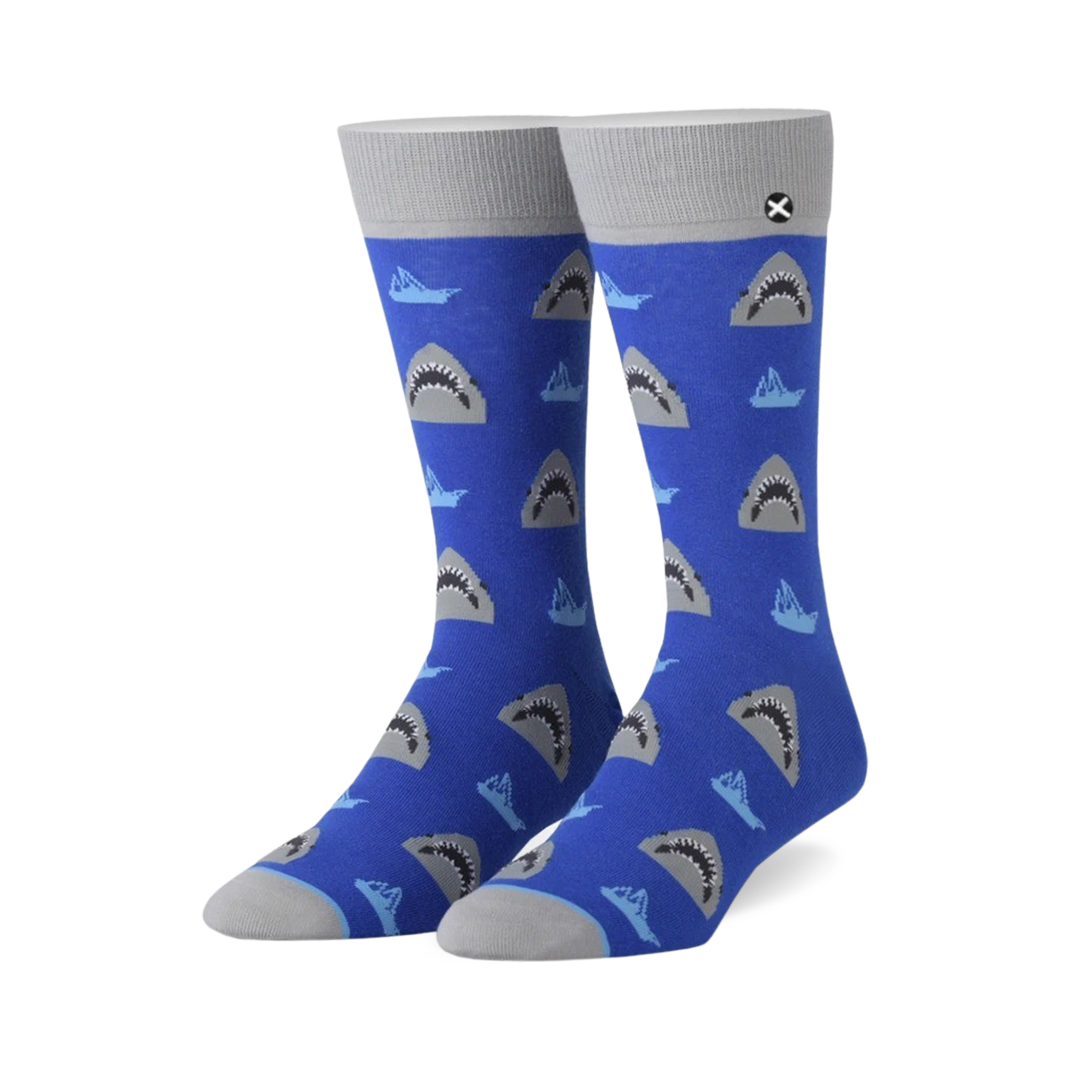A pair of blue crew socks with a repeating pattern of grey shark faces and small, light blue boats.  The socks have grey cuffs.