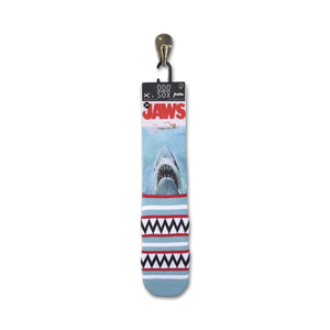 A pair of blue Odd Sox brand Jaws socks with a great white shark on the front and a red and white geometric pattern on the back.
