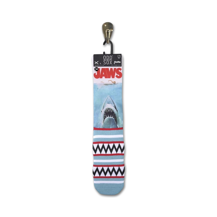 A pair of blue Odd Sox brand Jaws socks with a great white shark on the front and a red and white geometric pattern on the back.