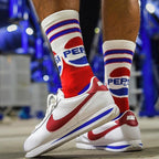 Person wearing Pepsi Throwback crew socks and white sneakers with red and blue accents, standing on concrete. [lf]