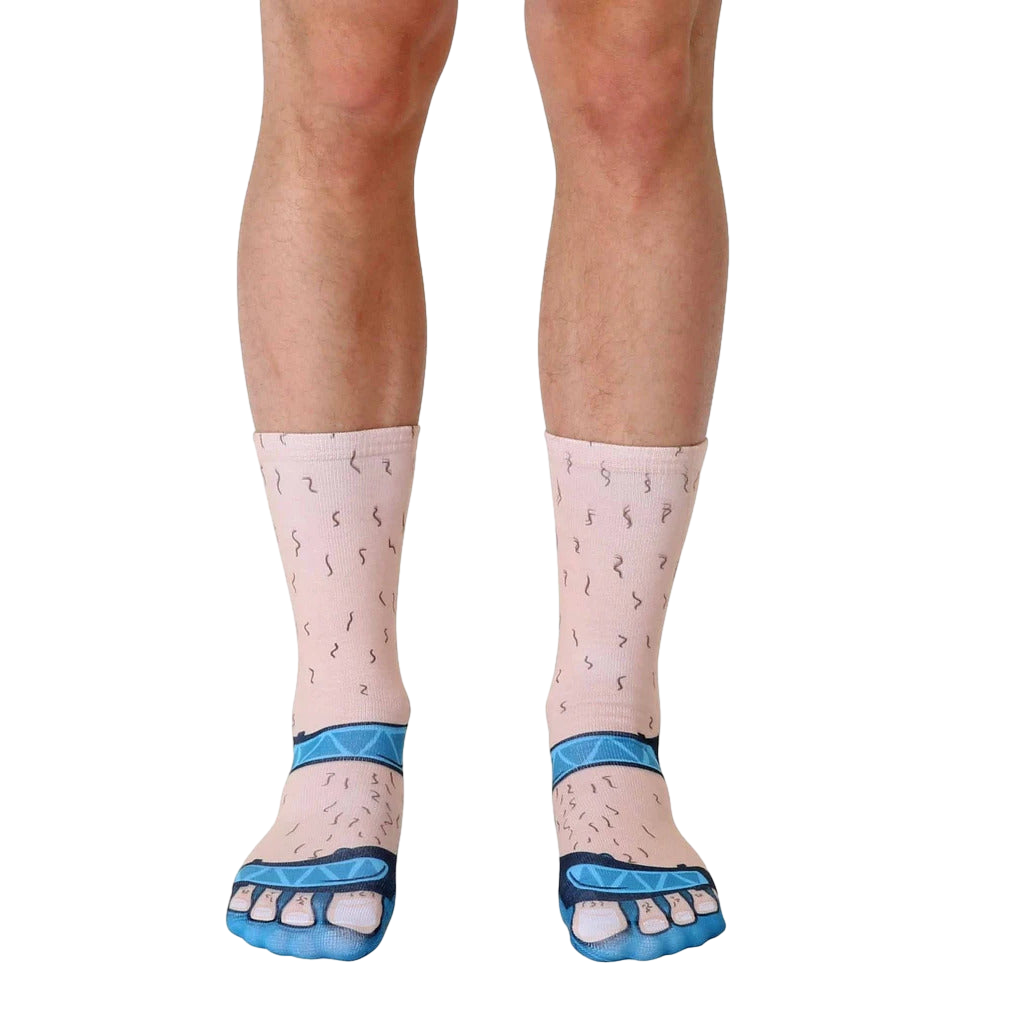 A pair of cream-colored crew socks depicting hairy legs wearing blue sandals.  Fun, novelty design. [lf]