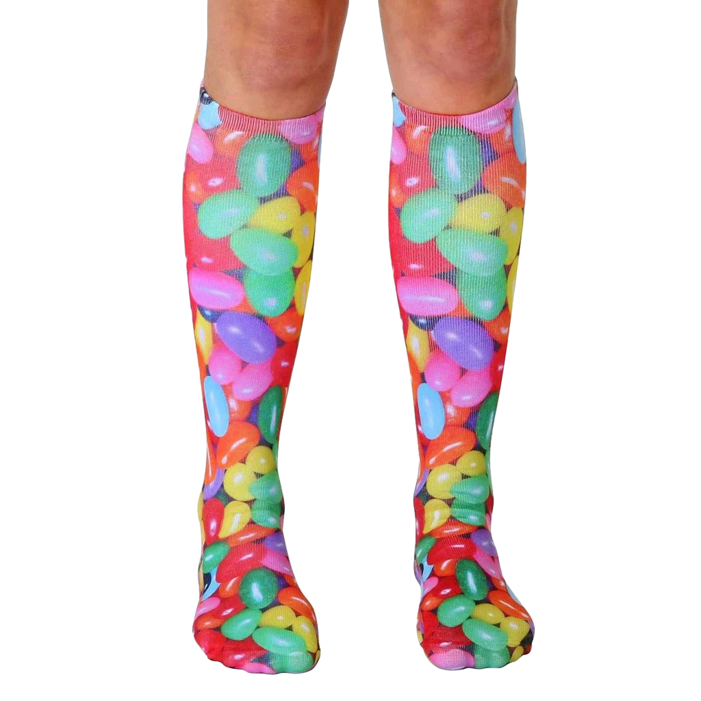 Pair of knee-high socks featuring a colorful jellybean print.  Red, green, yellow, pink, and purple jellybeans are scattered across a white background. [lf]
