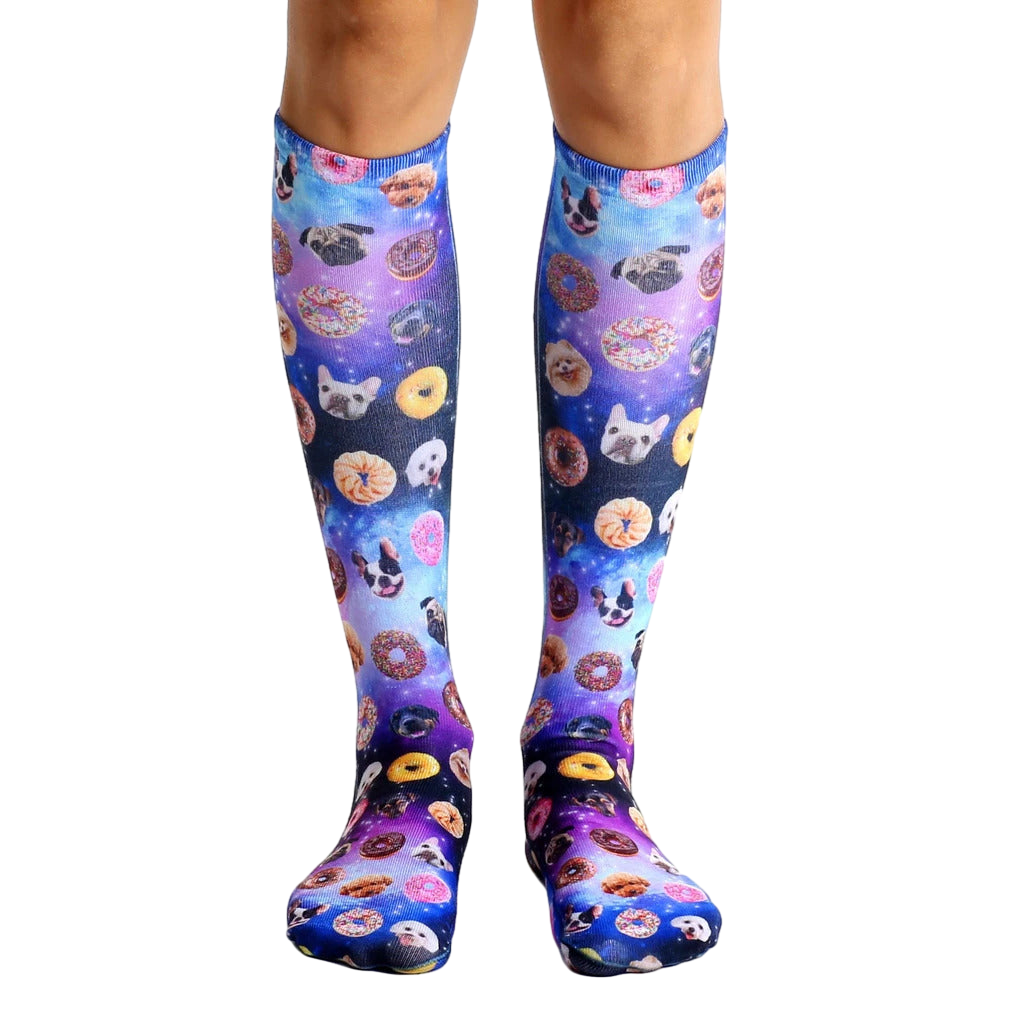 Pair of knee-high socks with a purple, pink, and blue galaxy print.  The print features various dog breeds and donuts. [lf]
