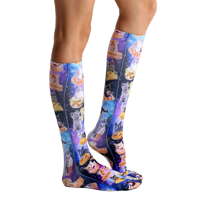 A pair of knee-high socks with a repeating pattern of cats wearing tacos, pizza, hamburgers, and waffles on a blue background with stars.