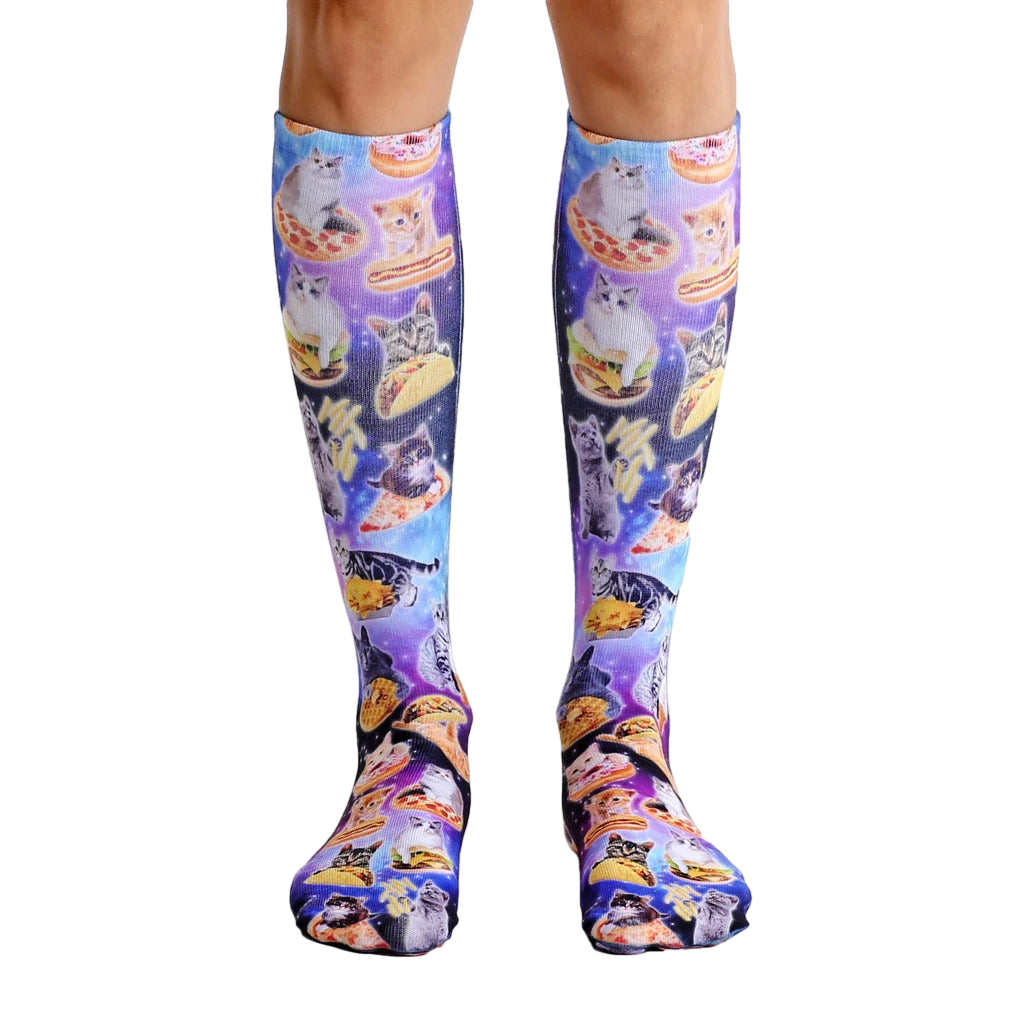 Pair of knee-high socks with a galaxy print. Kittens enjoying various foods like pizza and tacos are featured throughout the design. [lf]
