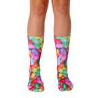 A pair of crew socks with a colorful jelly bean print.  The socks feature red, yellow, green, purple, and orange jelly beans on a white background. [lf]
