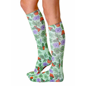A pair of green knee-high socks with a pattern of potted succulents and cacti.