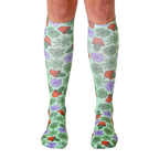 Pair of women's knee-high socks with a pastel green background and all-over print of succulents, cacti, and terracotta pots. [lf]