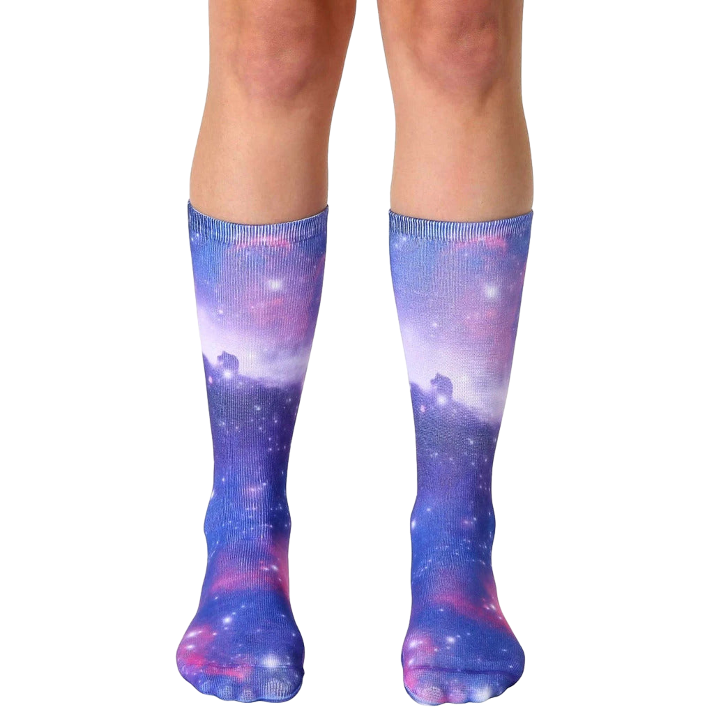 Pair of crew socks showcasing a vibrant galaxy print in shades of purple, pink, and blue. The design features nebulae and sparkling stars. [lf]