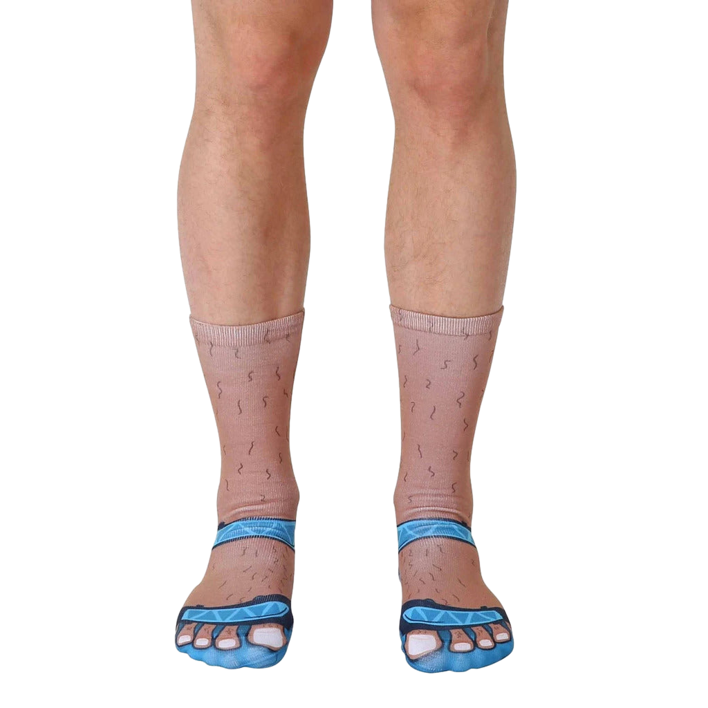 Close-up of a pair of novelty socks; tan-colored with hairy legs and light blue sandal designs on the toes. [lf]