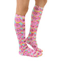 Lifestyle shot of a person wearing the pink donut knee-high socks. Shows the socks from the side. [lf]