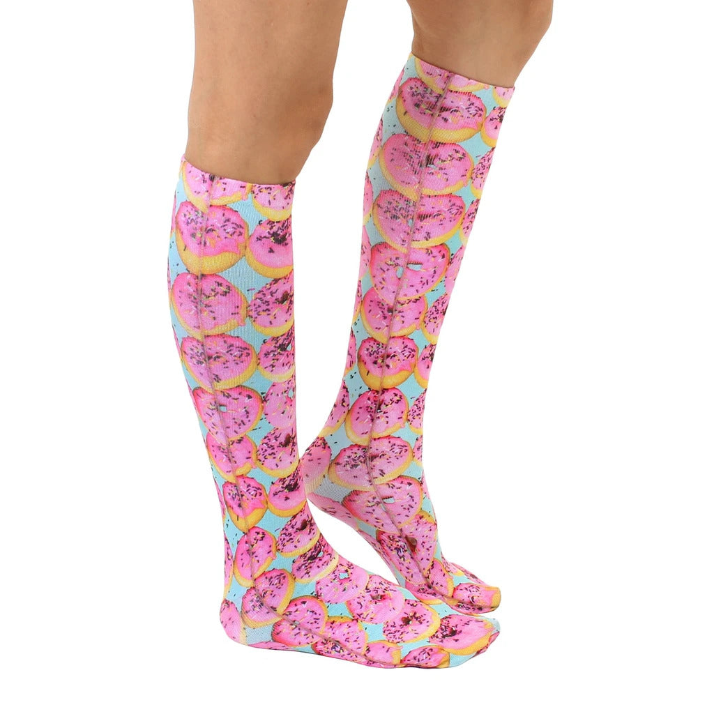 Lifestyle shot of a person wearing the pink donut knee-high socks. Shows the socks from the side. [lf]