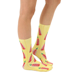 A pair of yellow socks with a pattern of red and green hot sauce bottles.