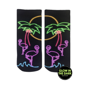 Pair of black ankle socks with a neon glow-in-the-dark design. Flamingos, palm trees, and a sunset are depicted in pink, purple, and green.