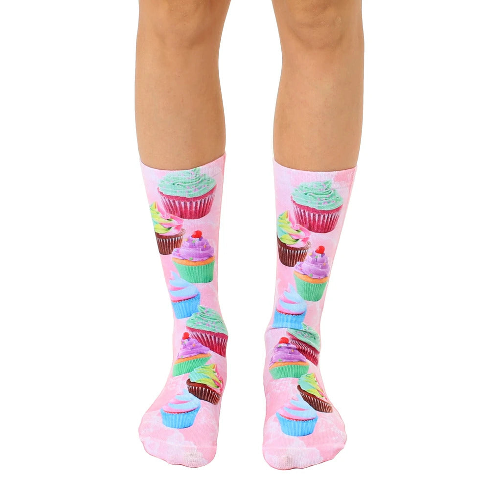 A pair of women's crew socks with a pink background and a fun all-over print of colorful cupcakes with pastel frosting. [lf]