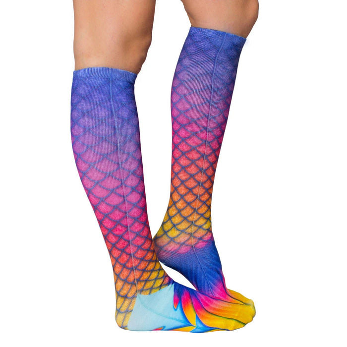 A pair of blue, pink, and purple mermaid tail socks with a scale pattern and yellow, orange, and pink fin design at the top.