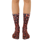 A pair of brown crew socks with an all-over print of coffee beans. Shown on a model's legs. [lf]