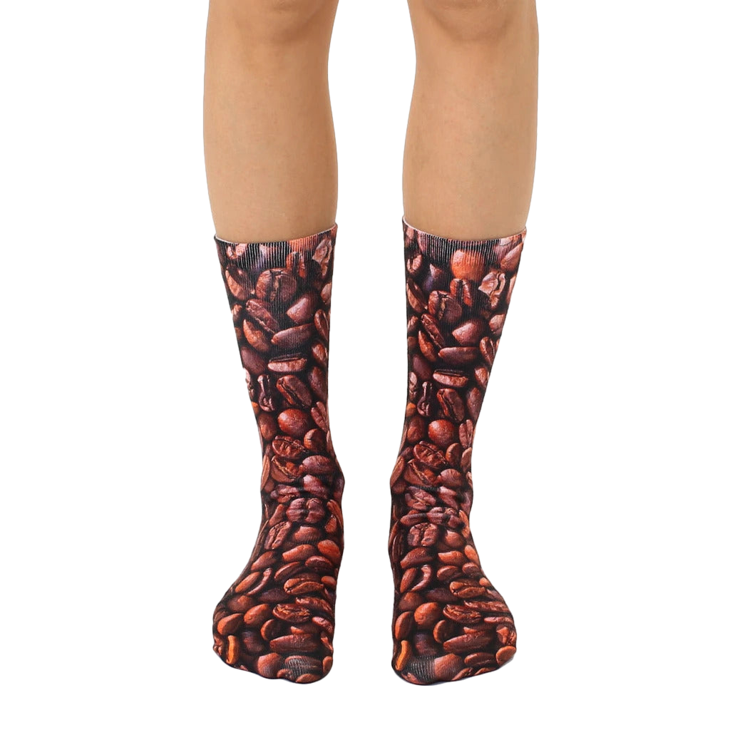A pair of brown crew socks with an all-over print of coffee beans. Shown on a model's legs. [lf]