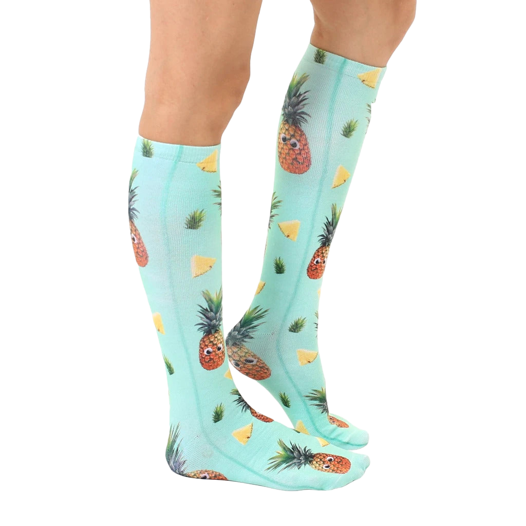 Lifestyle shot showing the Googly Pineapple knee-high socks on a person's legs, showcasing the sock's fit and pattern. [lf]