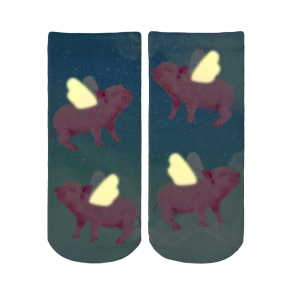 Ankle socks showcasing a whimsical design of pink pigs with glow-in-the-dark wings flying against a teal, starry sky. [lf]