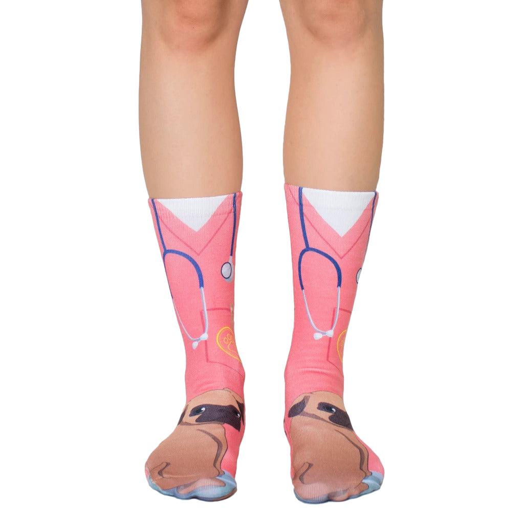 Pair of crew socks featuring a pink veterinary scrub design with a cute pug face at the bottom. Stethoscope and paw print details included. [lf]